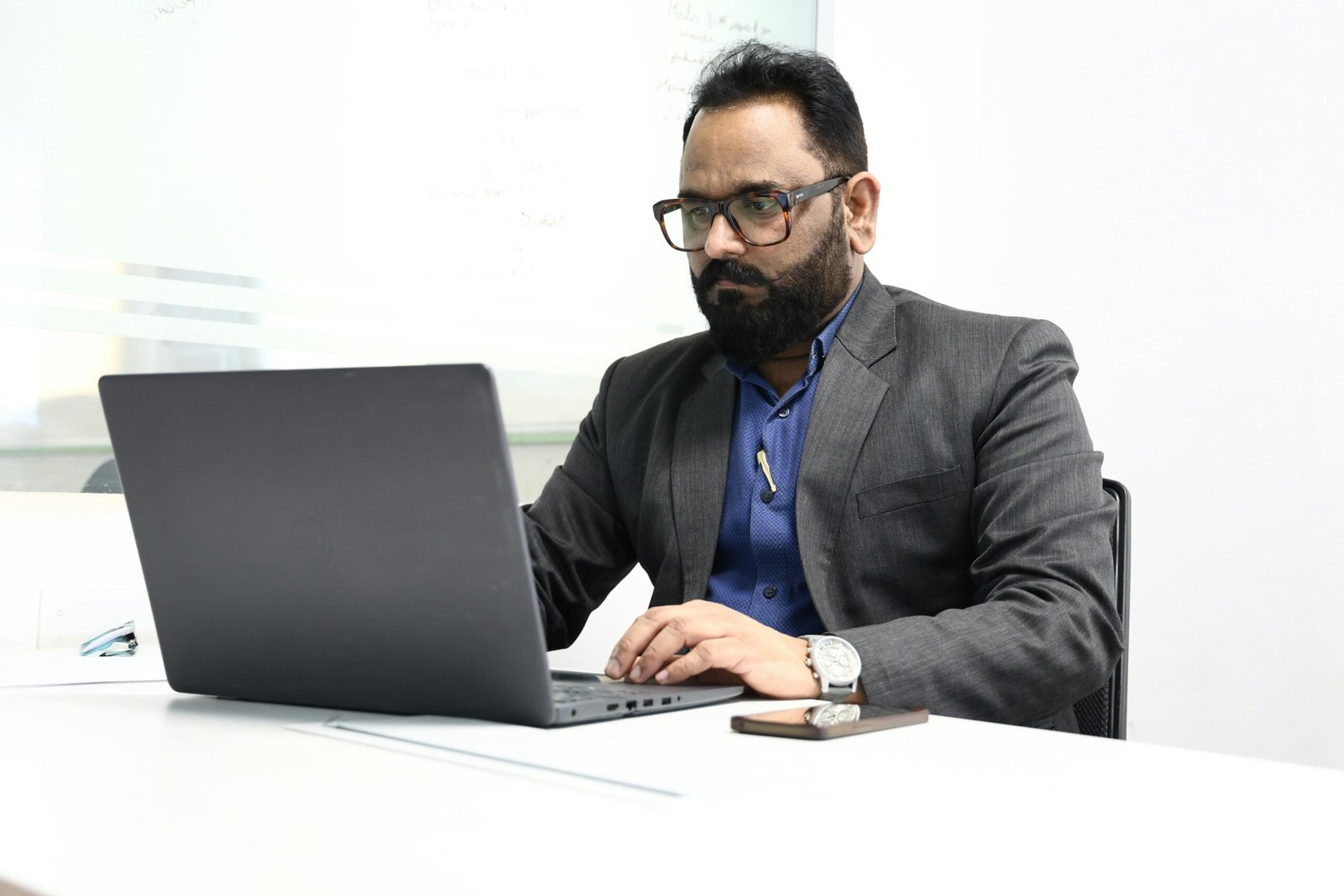 Professional adult businessman focused on his laptop in a modern office environment.
